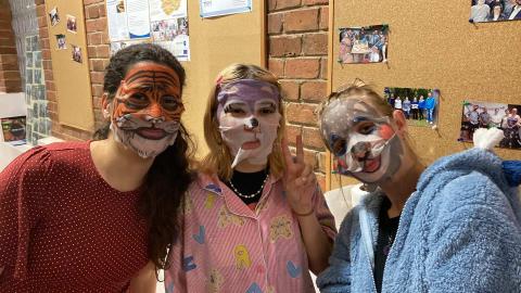 There are three ladies on the picture with facemask decorated as tiger, wolf, and bear.  